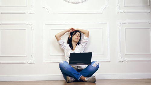 Young woman, girl, brunette, in white shirt and jeans, listening to music, using headphones 