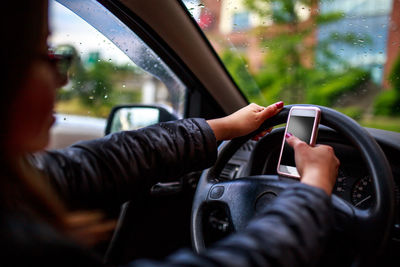 Midsection of woman using mobile phone in car