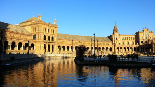 Reflection of building in water against clear blue sky