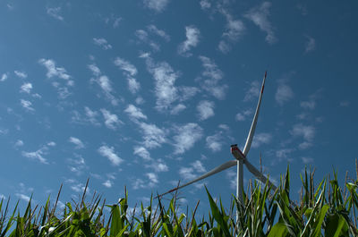Low angle view of wind turbines on field against sky