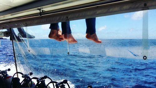 Low section of people sitting above aqualungs on boat sailing in sea