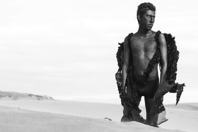 Teenage boy in costume on desert against sky