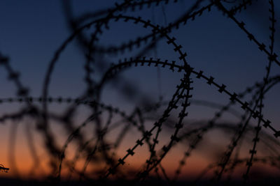 Low angle view of silhouette fence against sky during sunset