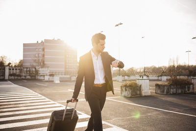 Businessman with rolling suitcase checking the time