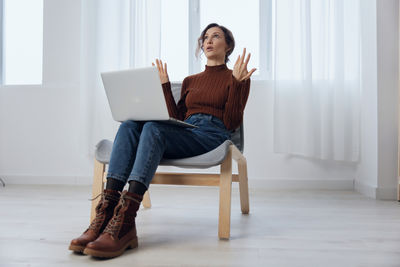 Young woman using laptop while sitting on sofa at home