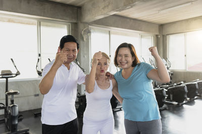 Portrait of man and woman showing fists while standing in gym