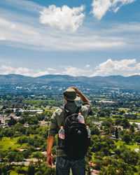 Rear view of man standing on mountain against sky