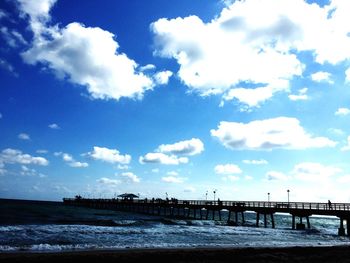 Bridge over sea against cloudy sky