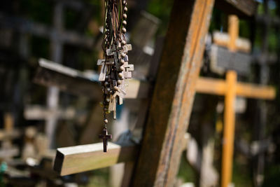 Close-up of bead necklaces against cross at cemetery