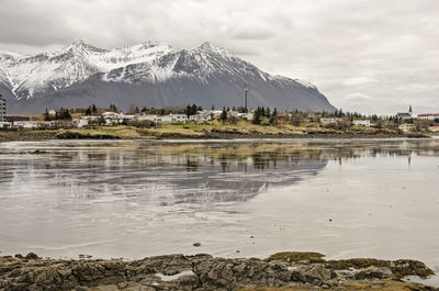 The town and the mountains behind it reflecting on the mudflats in the fjord at low tide