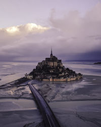 View of building by sea against cloudy sky