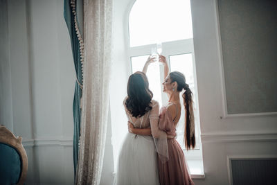 Bridesmaid and bride holding champagne flute