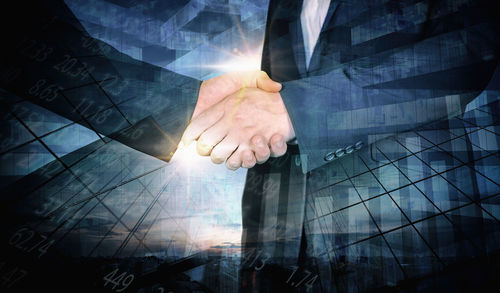 Double exposure image of businessmen shaking hands and city