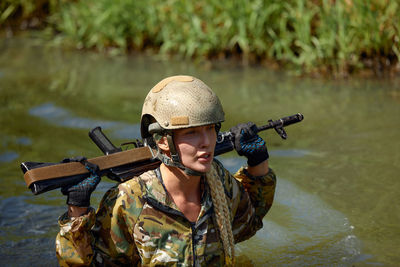 Rear view of woman wearing hat standing in lake