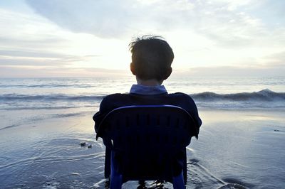 Rear view of man looking at sea against sky