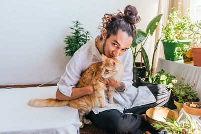 Portrait of young man holding cat sitting at spa