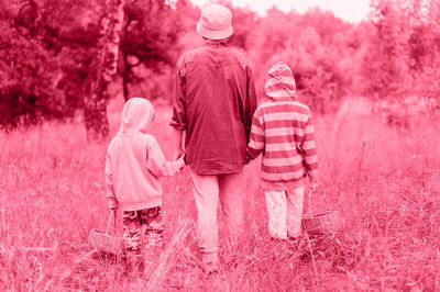 Little kids mushroom pickers go forest by hand with grandmother. family. toned in viva magenta