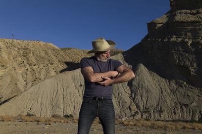 Adult man in cowboy hat on desert against mountain. almeria, spain