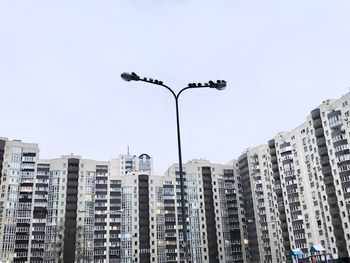 Low angle view of buildings  and street light with birds on it against clear sky