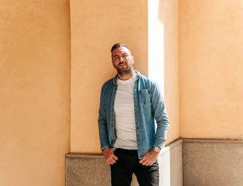 Portrait of young man standing against wall