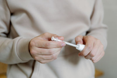 A young man draws up medicine with a syringe.