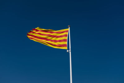 Low angle view of flag against blue sky