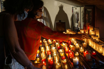 Young woman standing by illuminated candles