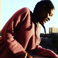 Man sitting against sky in city