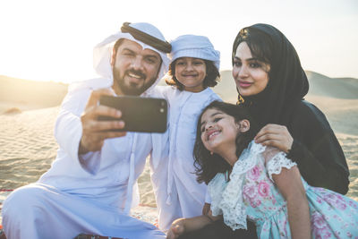 Happy family taking selfie with phone at desert