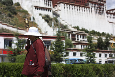 Rear view of man standing against buildings in city