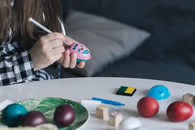 Midsection of girl coloring easter egg on table