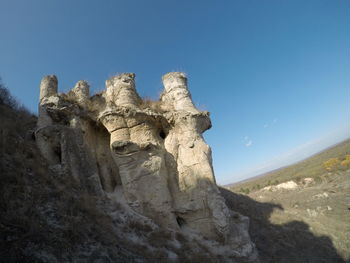 Low angle view of rock formation against clear blue sky