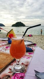 Close-up of drink on table at beach against sky