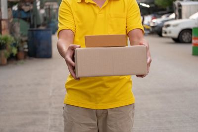 Midsection of man holding yellow while standing in car