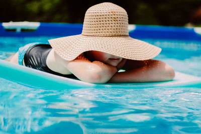 Girl lying on pool raft in swimming pool