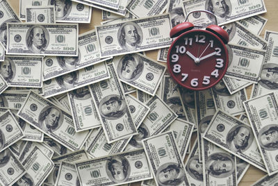 High angle view of alarm clock with paper currencies on table