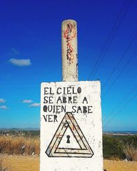 Close-up of road sign against blue sky