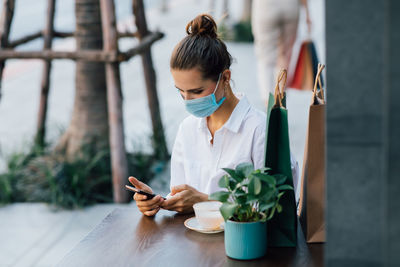 Young woman using mobile phone on table