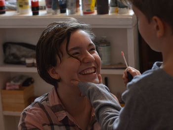 Brother applying lip gloss for sister at home