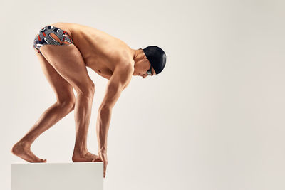 Midsection of shirtless man standing against white background