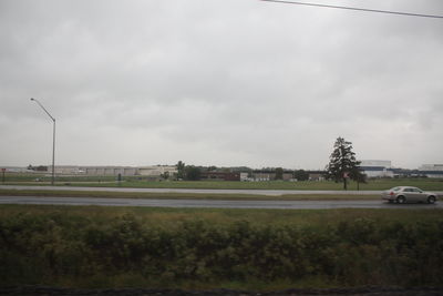 Trees on field against cloudy sky