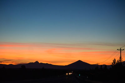 Silhouette mountains against orange sky