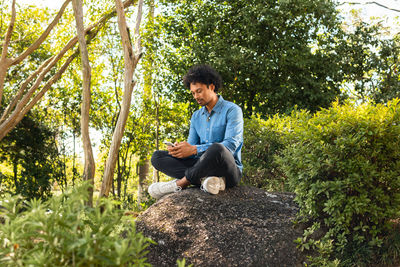 Young man sitting on rock in forest