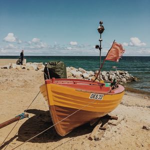 Boat moored at beach against sky