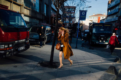 Full length of woman with cars in city