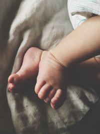 Low section of baby lying on bed