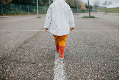 Rear view of woman walking on road