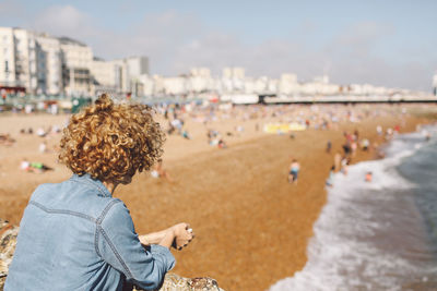 Rear view of woman at beach against sky