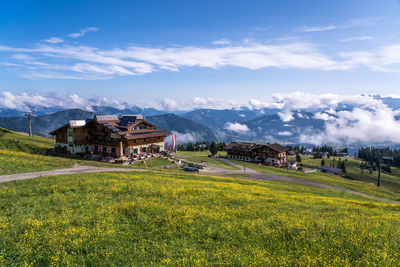 Scenic view of field by houses against sky