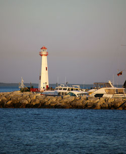 Lighthouse by sea against clear sky